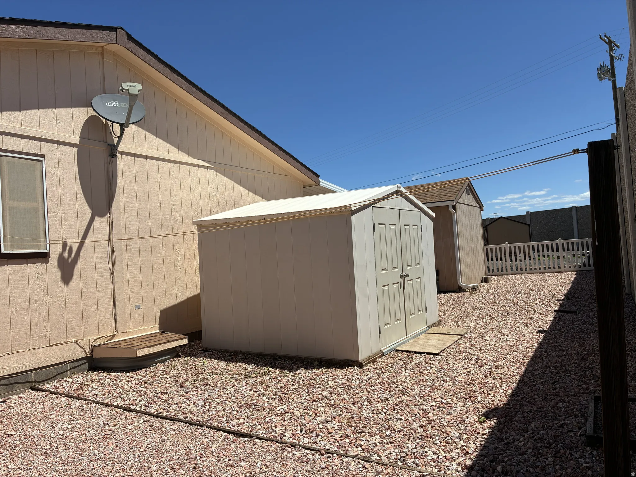 Side yard featuring gravel landscaping and a storage shed and clothes line