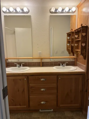 Double vanity with wood-finish cabinetry, integrated sinks, and individual mirrors
