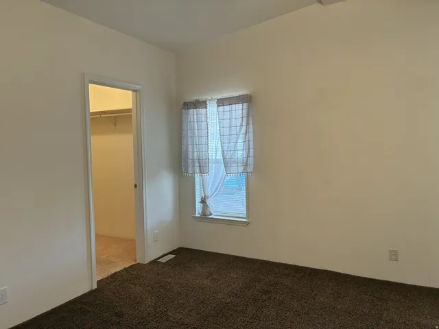 Primary bedroom with 2 windows with blinds, and a walk-in closet