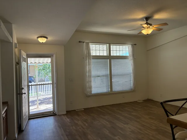 Spacious living area featuring LVP flooring, a multi-pane window with blinds, a storm door and a ceiling fan with integrated lighting