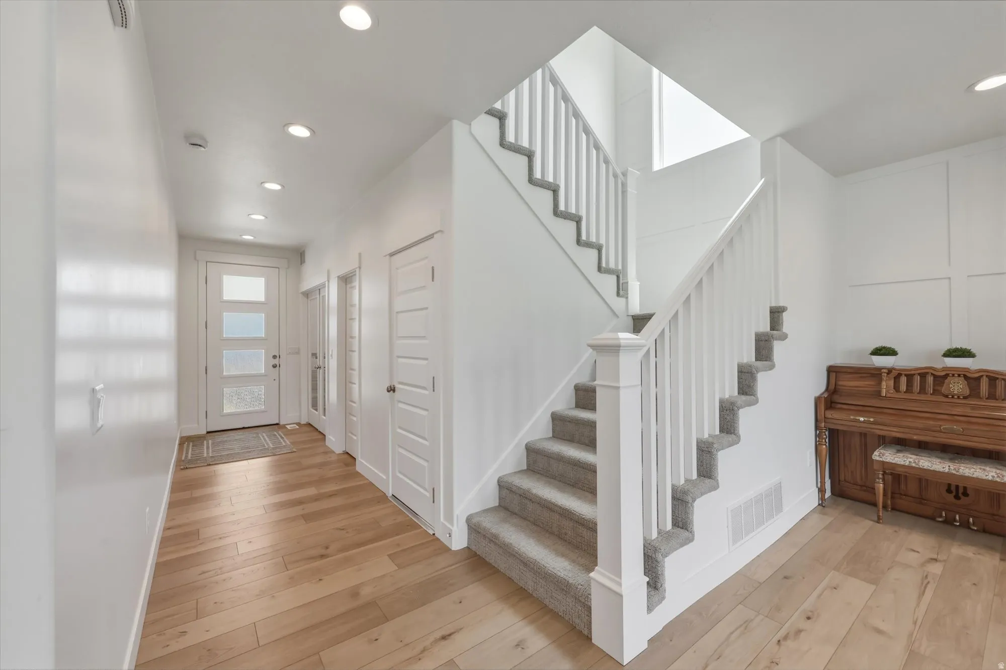 Entryway featuring wood-finish flooring, a contemporary front door with frosted glass panels, and recessed lighting
