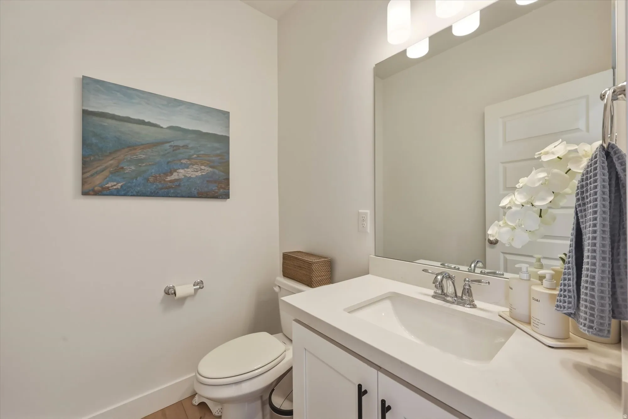 Bathroom featuring a white vanity with an integrated sink, polished chrome faucet, and a wall-mounted rectangular mirror
