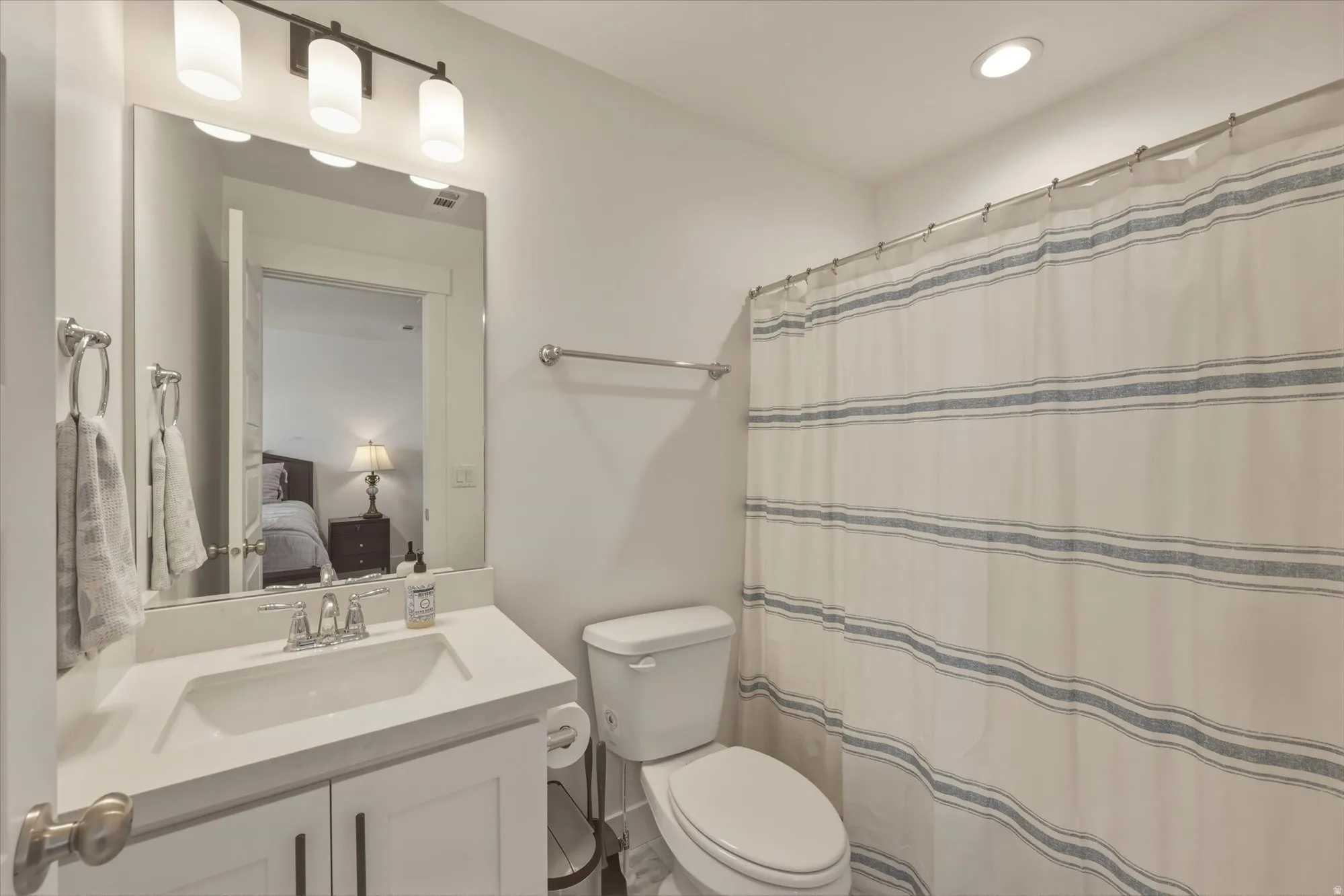 Contemporary bathroom featuring a white vanity with an integrated sink, polished chrome faucet, and dark bronze three-light fixture