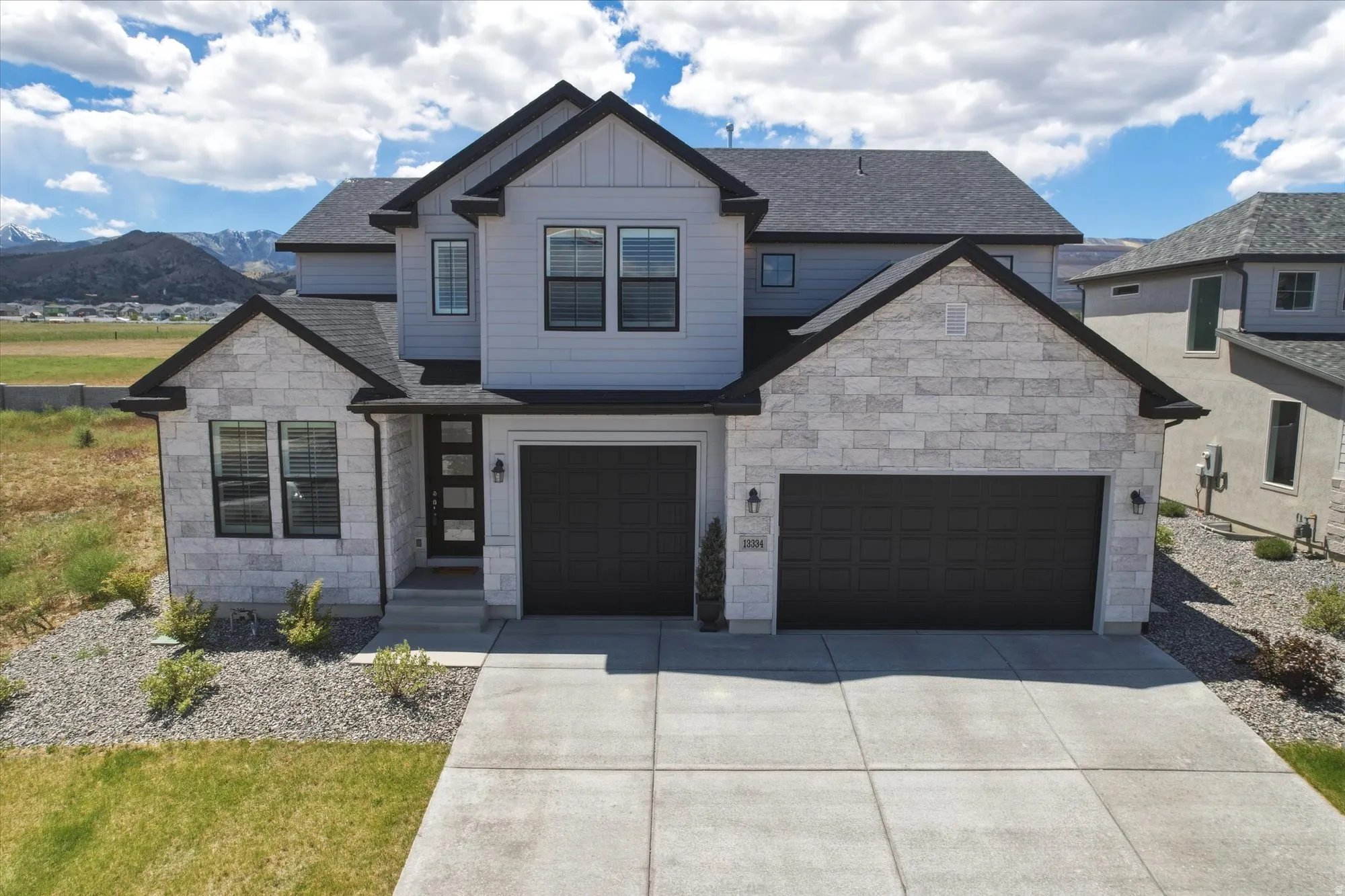 Modern contemporary facade featuring light gray siding and light-colored stone accents