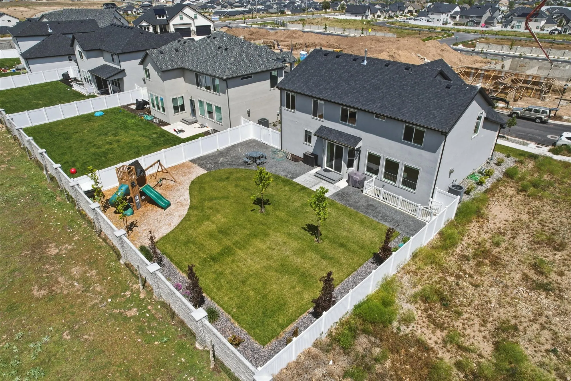 Backyard featuring a manicured lawn, white privacy fencing, and a built-in patio area