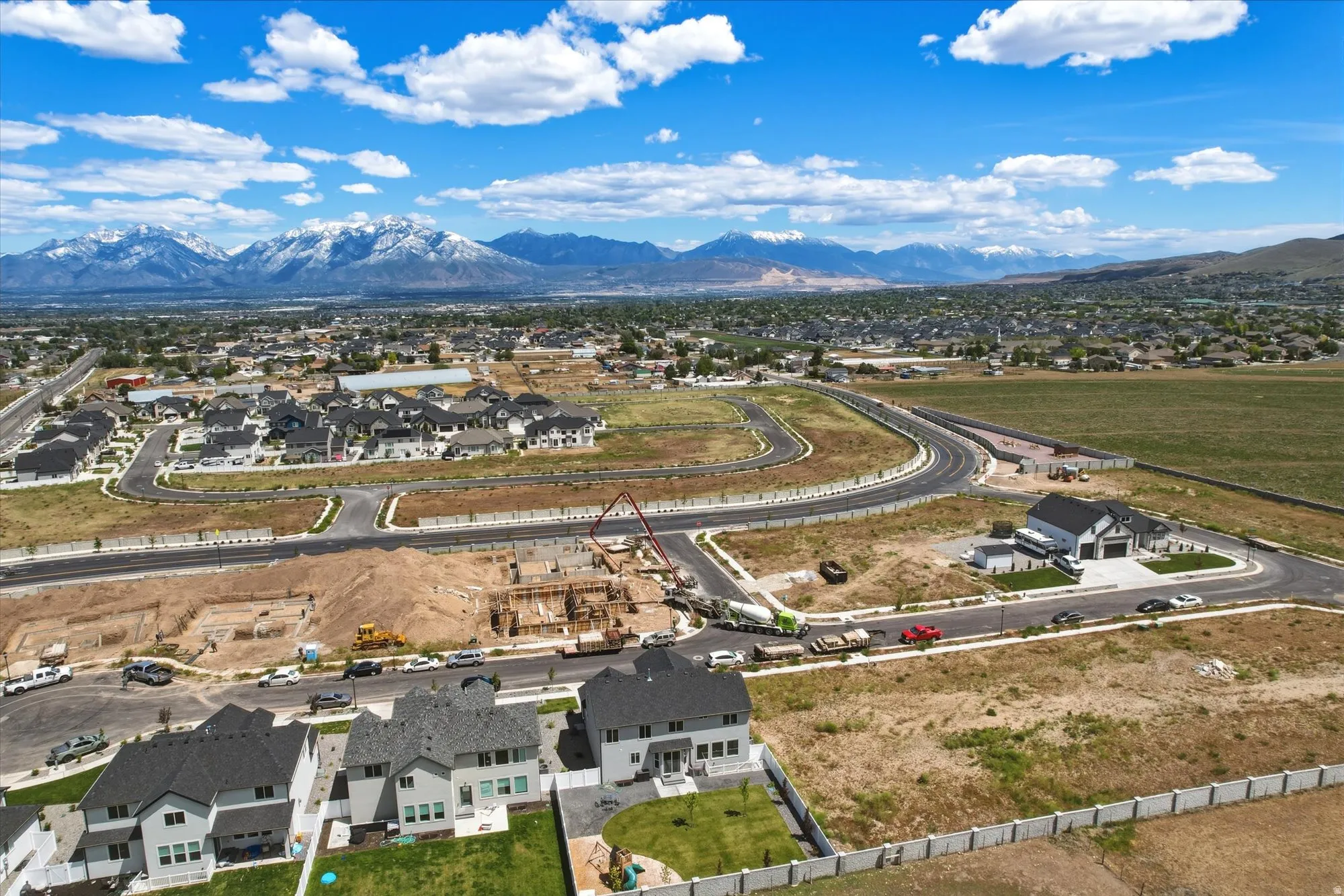 Expansive aerial perspective showcasing a developing residential area with snow-capped mountains in the background