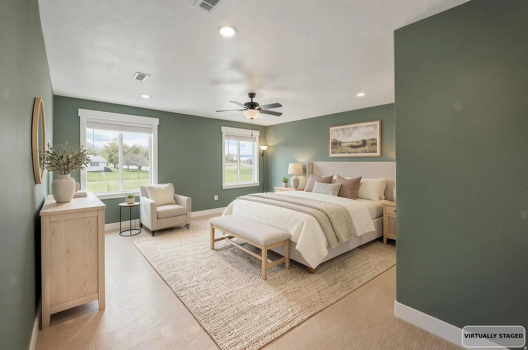 Virtually Staged- Spacious primary suit featuring light wood-finish flooring, recessed lighting, and a ceiling fan