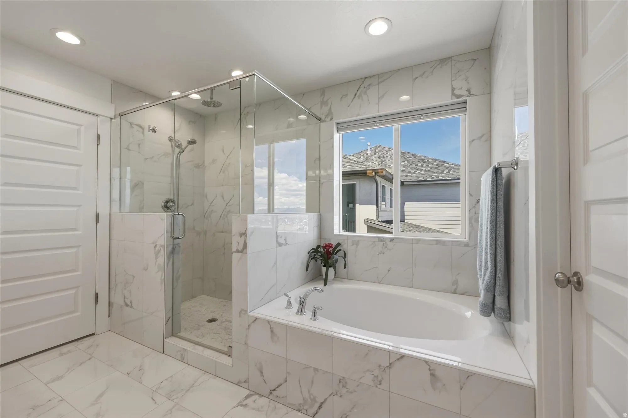 Spacious bathroom featuring a glass-enclosed shower with subway tile, a built-in bathtub, and white paneled doors