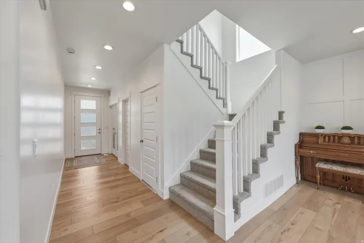 Entryway featuring wood-finish flooring, a contemporary front door with frosted glass panels, and recessed lighting