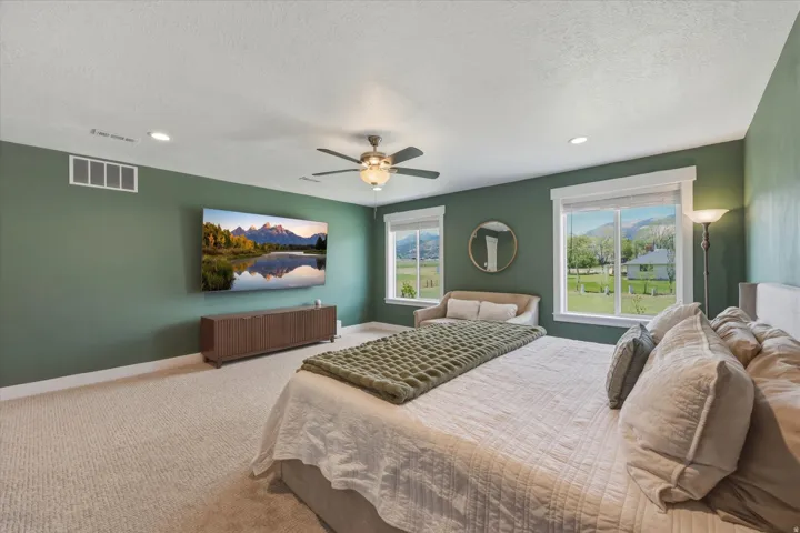 Carpeted room featuring a ceiling fan with integrated lighting, two large windows, and recessed ceiling lights