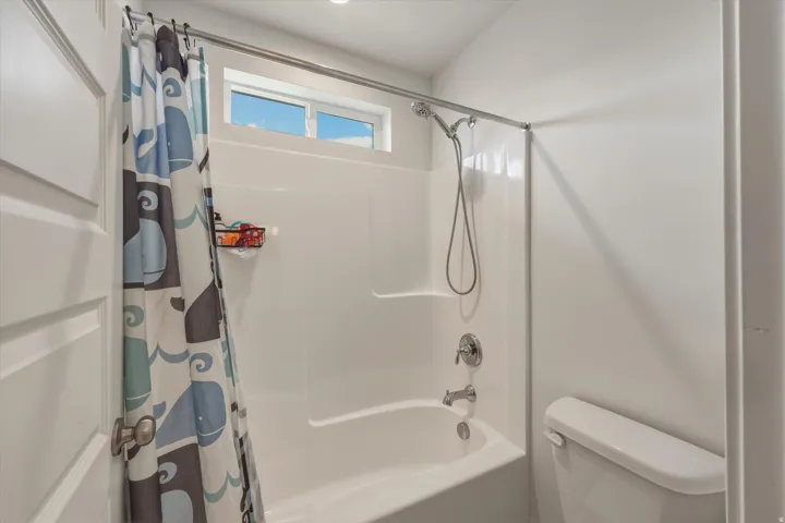 White tub and shower combination with a fixed showerhead, handheld sprayer, and chrome fixtures