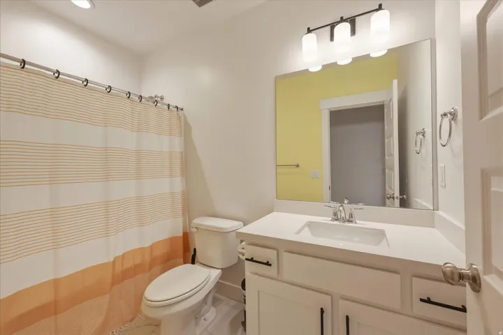Bathroom featuring a white vanity with an integrated rectangular sink, a large frameless mirror, and a three-light vanity fixture