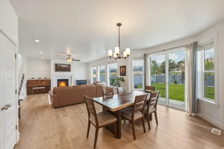 Open-concept living area featuring wood-finish flooring, a fireplace with a white mantel, and extensive windows