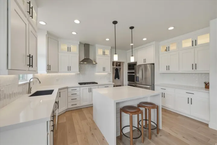 Contemporary kitchen featuring white cabinetry, light countertops, wood-finish flooring, a central island, and stainless steel appliances