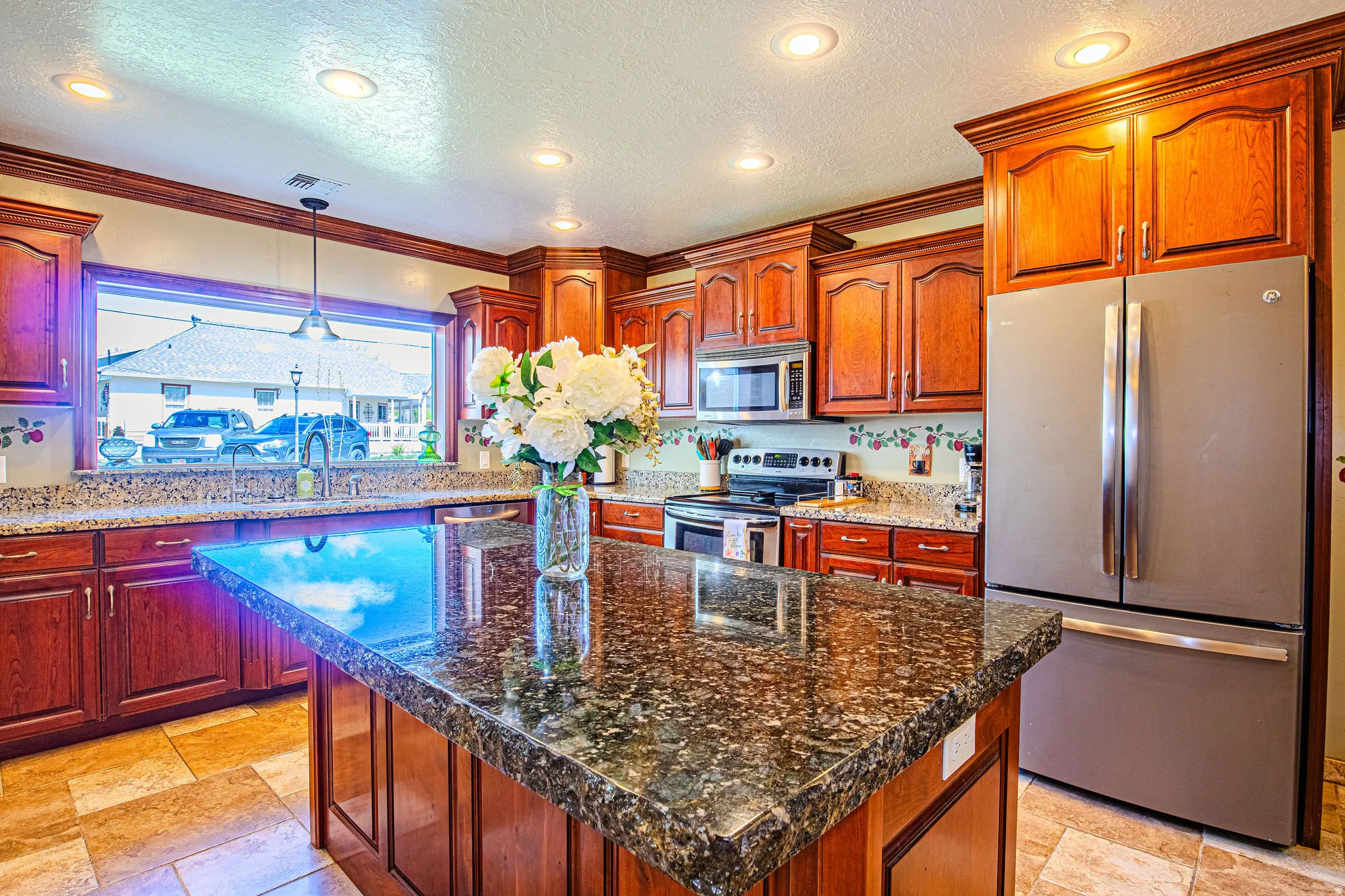Kitchen featuring a large island with a speckled countertop, extensive wood cabinetry, stainless steel appliances, recessed lighting, and tile flooring