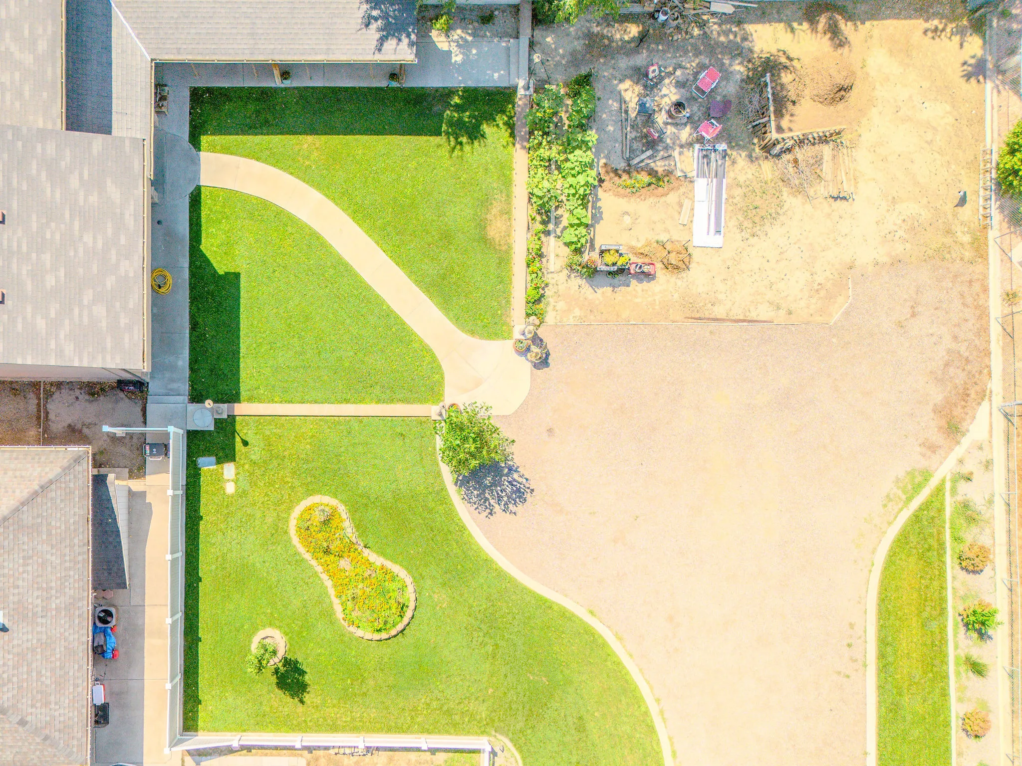 Manicured lawn with a curved paved pathway, mature trees, and a decorative garden bed