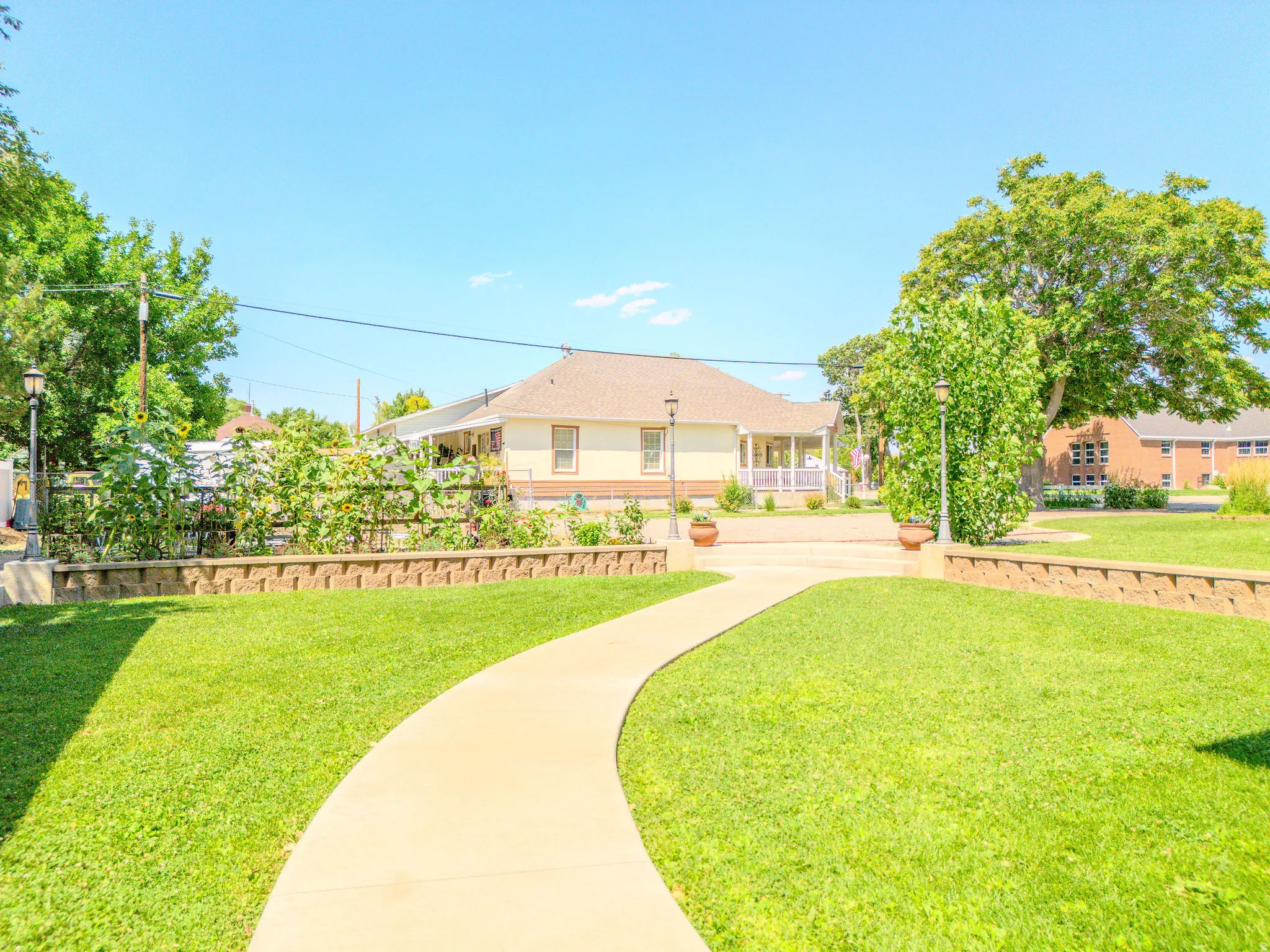 Curved concrete pathway leading to a residence with a covered porch and white railings