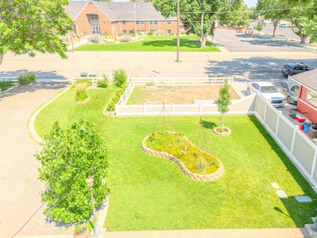 Landscaped yard with a shaped garden bed, stone-edged planting areas, and a paved driveway