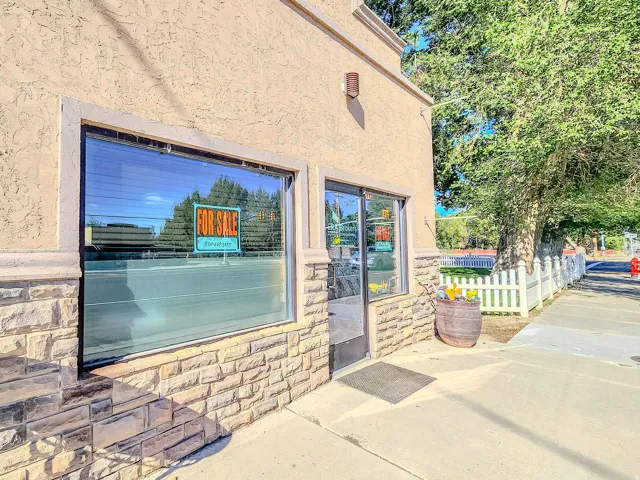 Stucco facade with stone accent detailing, large storefront windows, and a glass-paneled entry door