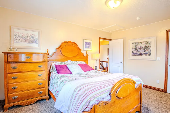 Second carpeted bedroom featuring a flush-mount ceiling light, white trim, and a white door leading to an interior space with a visible staircase