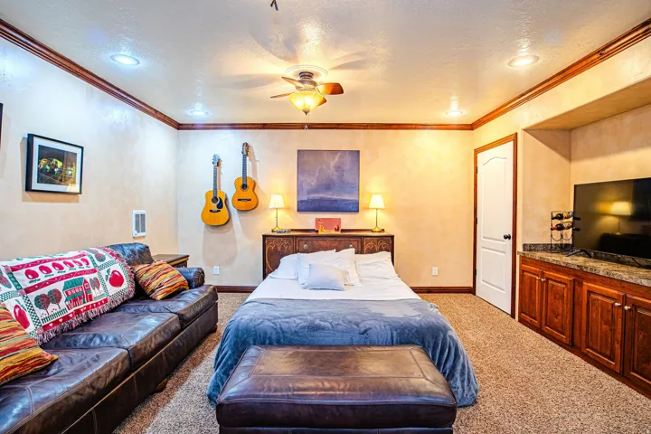 Spacious room featuring ceiling-mounted lighting, crown molding, and textured walls. Temporary bed for extra guests