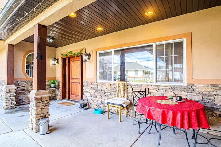 Covered patio entrance featuring stacked stone accents, stucco siding, and recessed lighting