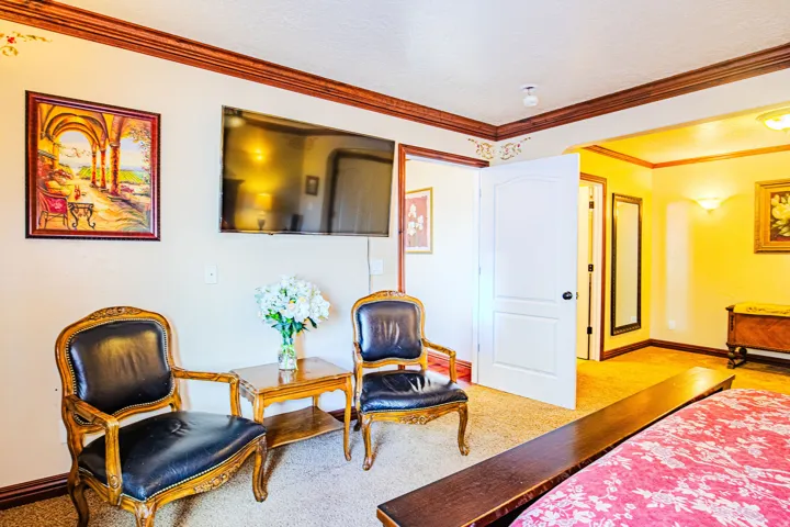 Carpeted Master bedroom room featuring crown molding, a built-in wall-mounted television, and a classic-style door