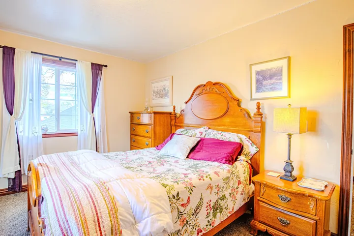Carpeted second bedroom with a double-pane window featuring wood trim