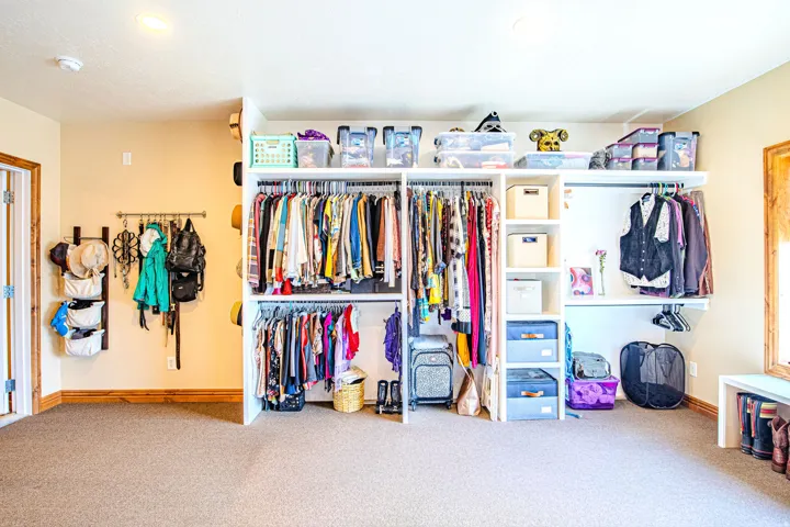 Customizable closet system featuring multiple hanging rods, open shelving, and built-in storage in second living space bedroom