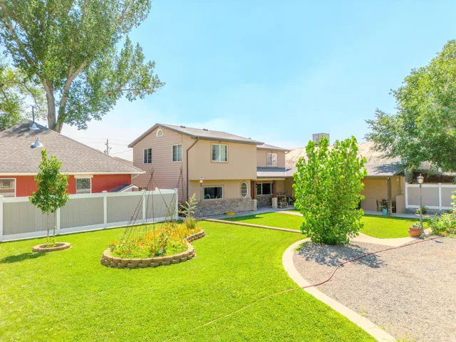 Expansive lawn with an oval-shaped planting bed, gravel pathway, and privacy fencing