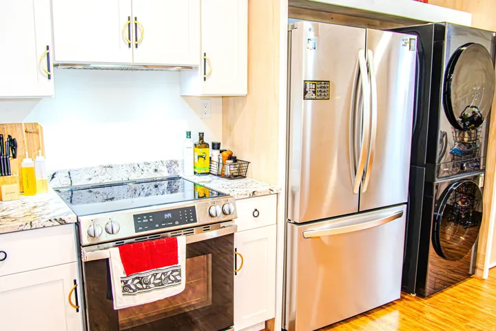 Kitchen featuring white shaker cabinetry with gold and black hardware, granite countertops, a stainless steel electric range, and a stainless steel French door refrigerator