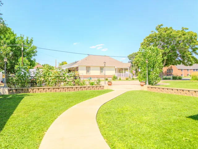 Curved concrete pathway leading to a residence with a covered porch and white railings