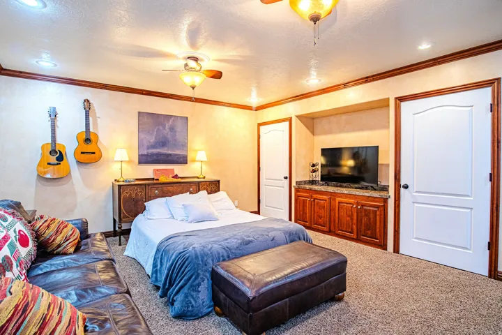 Recessed lighting and ceiling fans illuminate a carpeted room featuring a built-in media center with wood cabinetry and a dark countertop