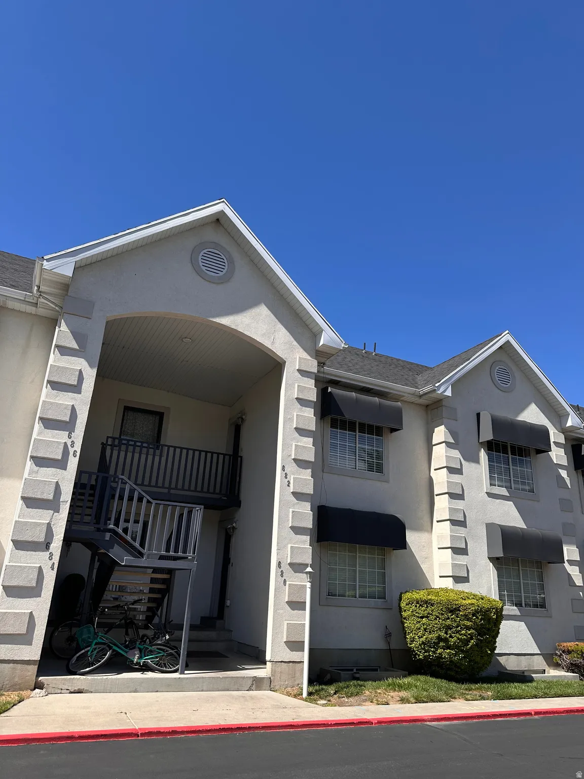 Multi-story building featuring a light stucco exterior with decorative quoins and dark awnings over windows