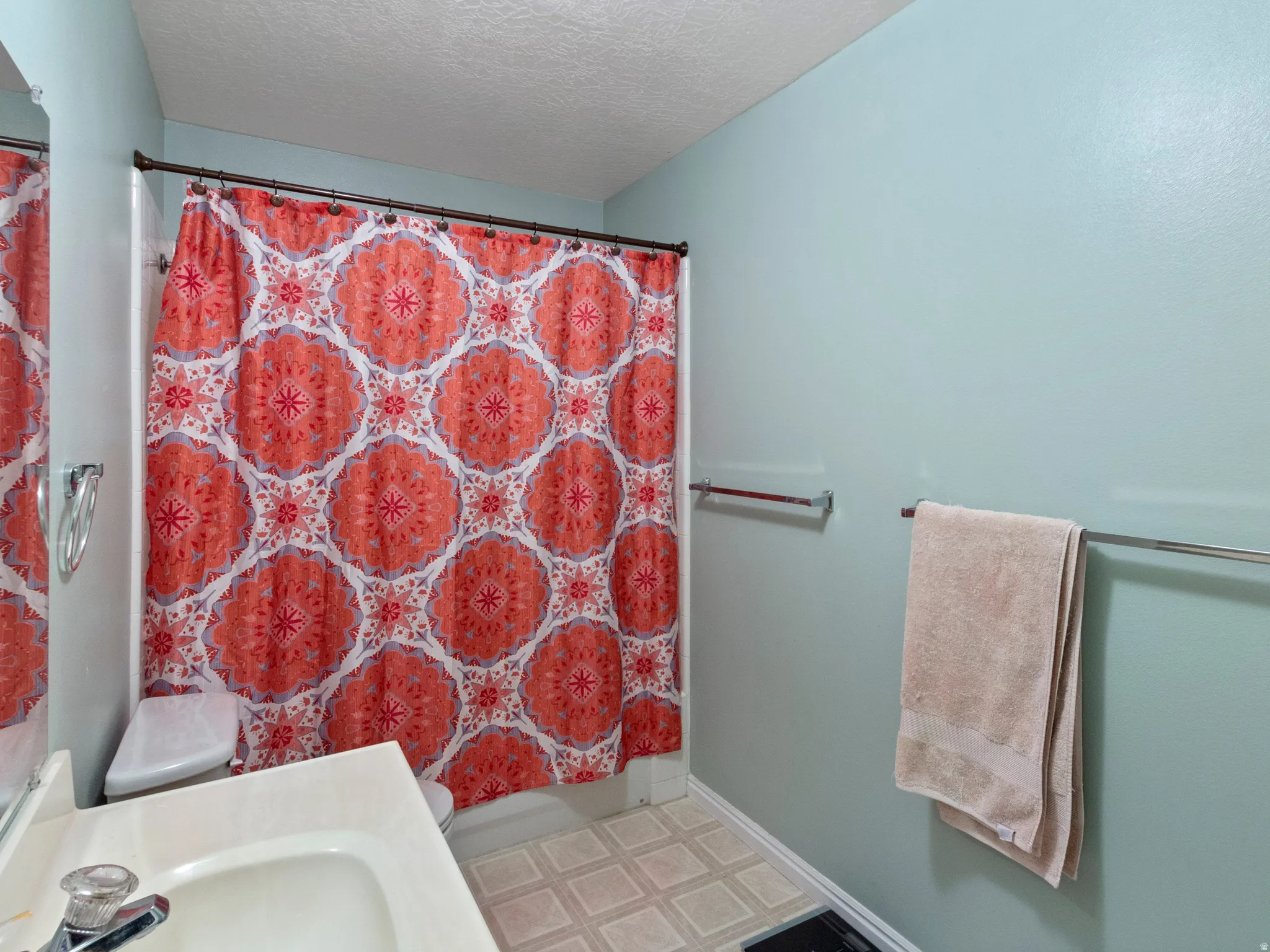 Bathroom featuring a built-in tub with shower, light blue walls, and durable vinyl flooring