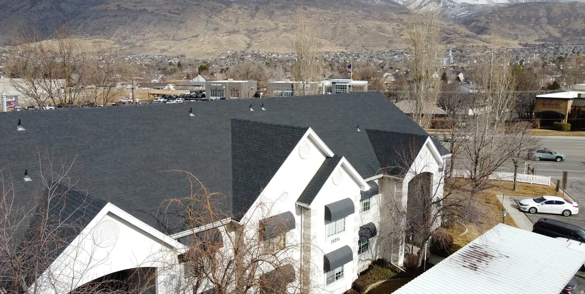 Multi-story building featuring a dark shingle roof, white exterior siding, and multiple window awnings