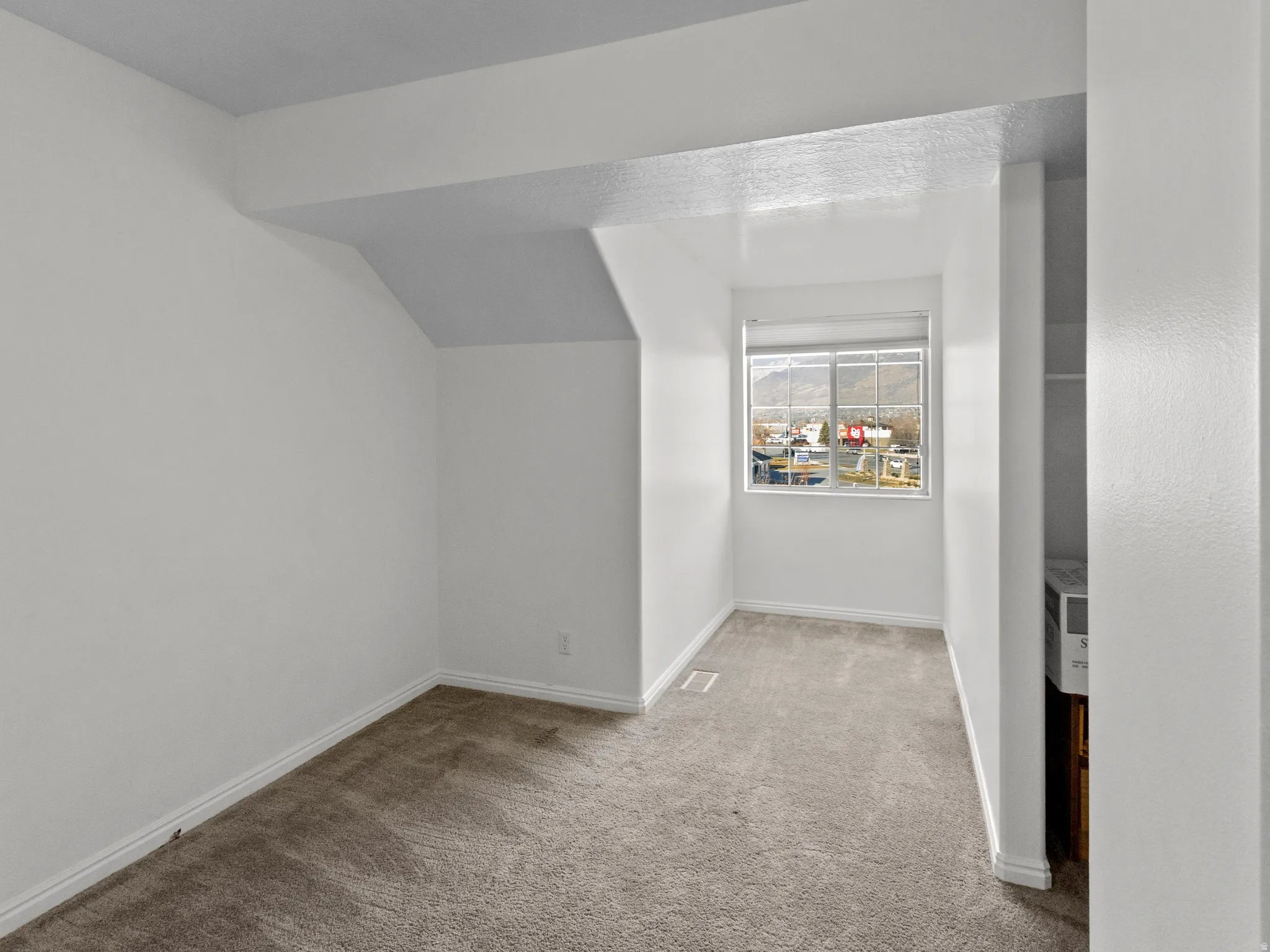 Carpeted room with a double-pane window, white trim, and a partial closet space