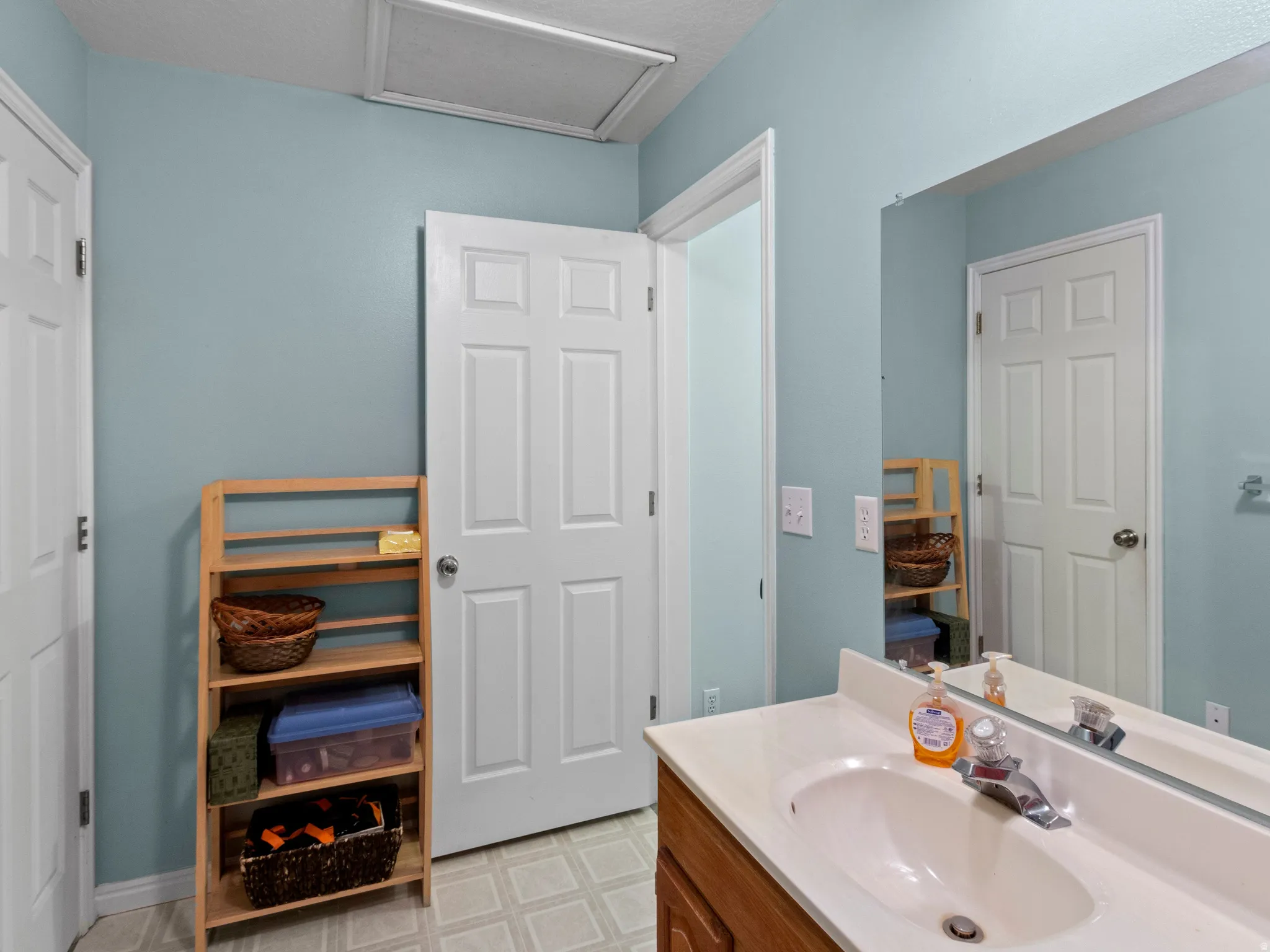Bathroom vanity featuring a light-colored countertop with an integrated sink, chrome faucet, and a wall-mounted mirror