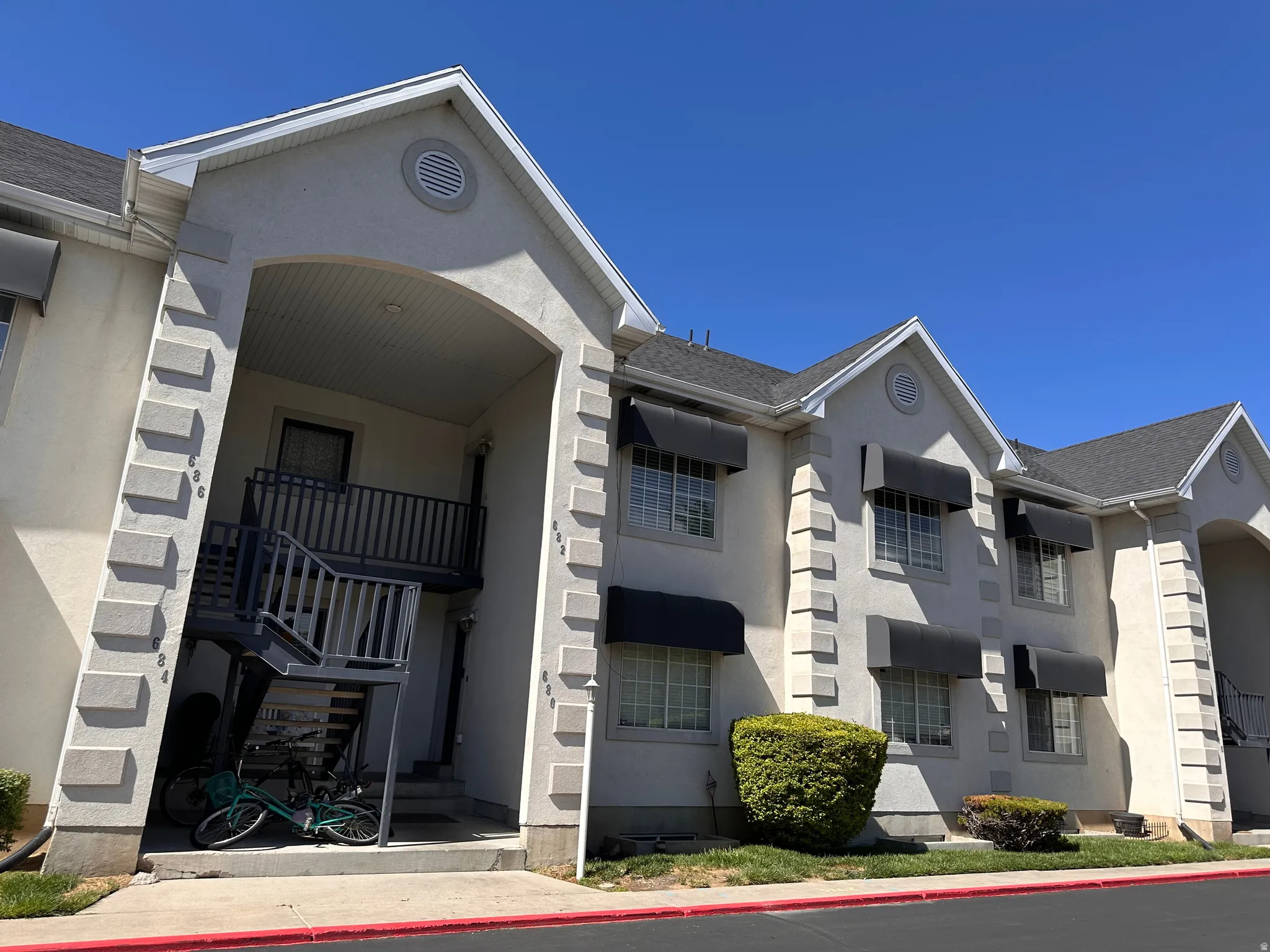 Multi-story building exterior featuring stucco siding and dark roof shingles