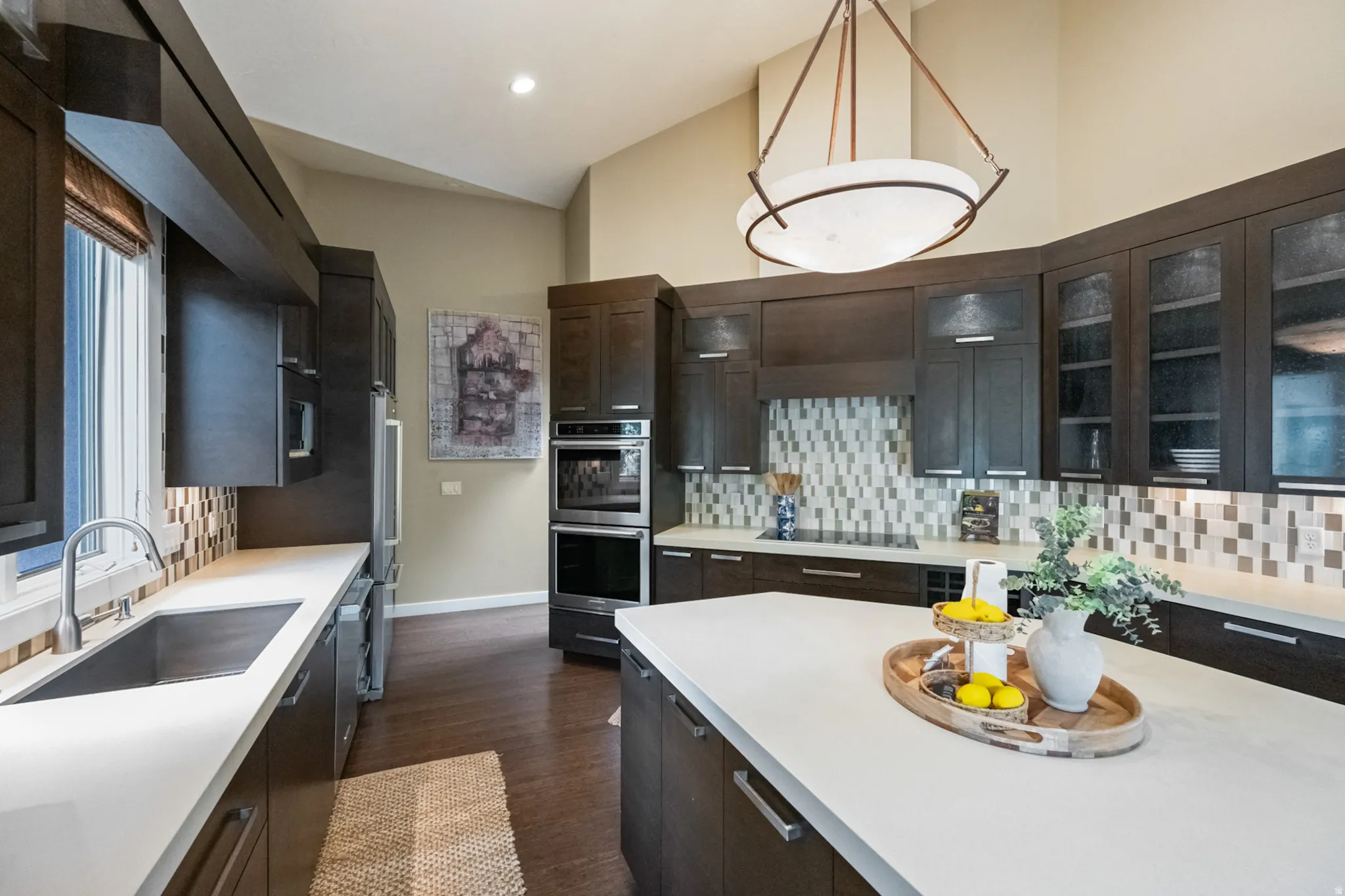 Spacious kitchen featuring dark wood cabinetry, light-toned countertops, and a full tile backsplash
