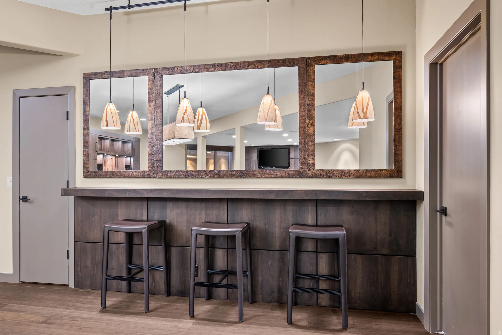 Built-in bar with dark wood-finish cabinetry, a coordinating countertop, and three pendant lights
