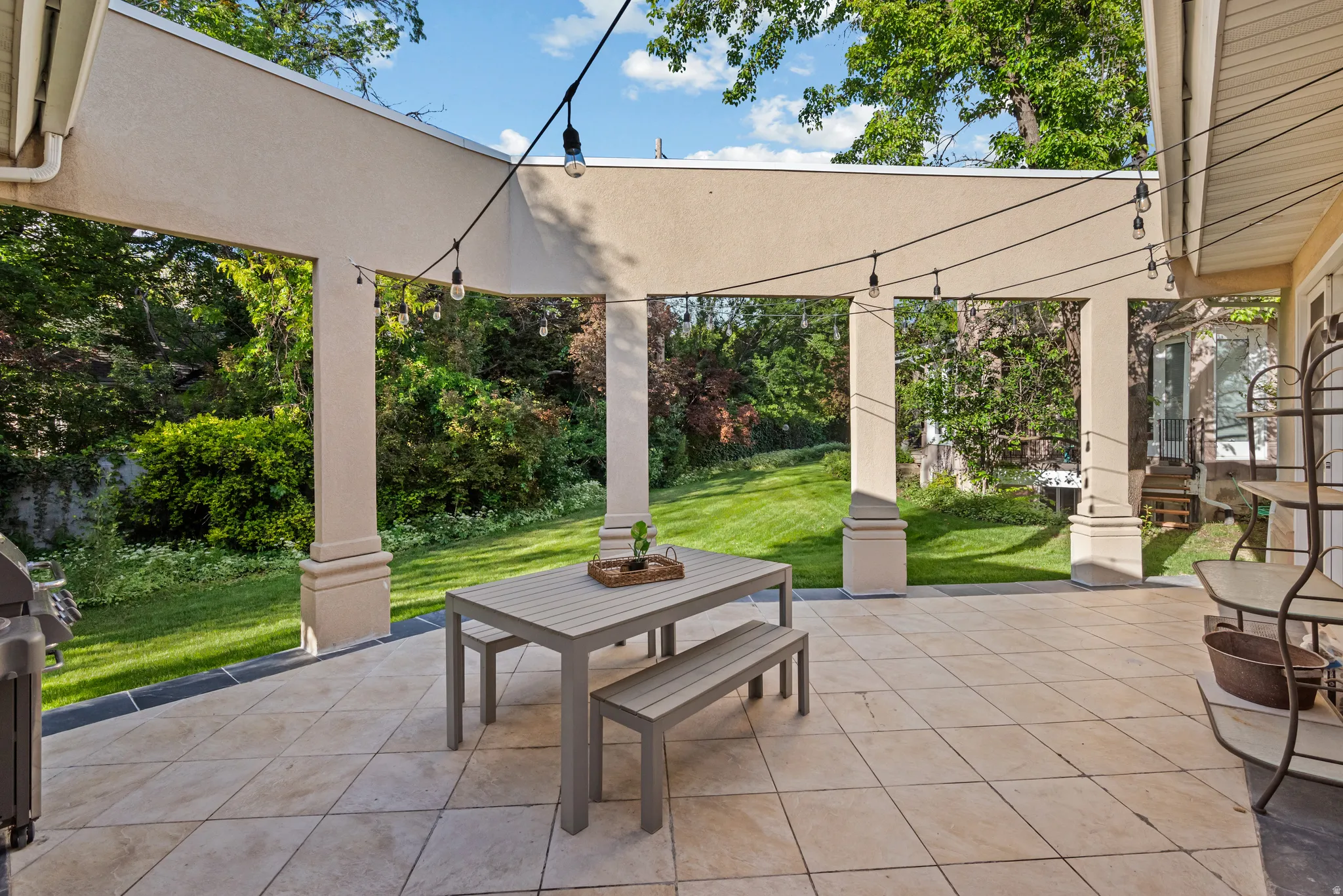 Expansive covered patio featuring a tiled surface, string lighting, and direct access to a grassy yard