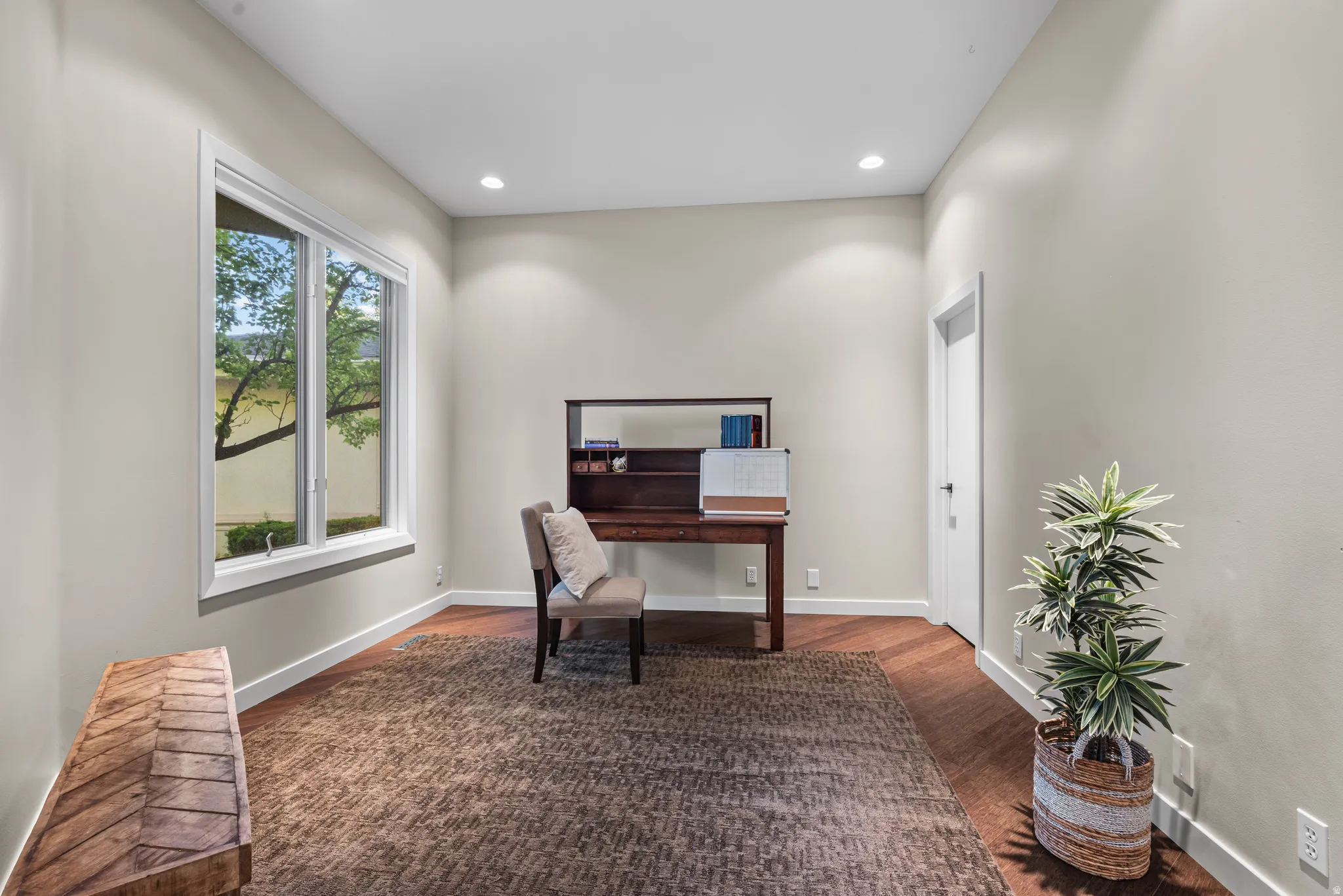 Room featuring wood-finish flooring, recessed lighting, and a large window with white trim