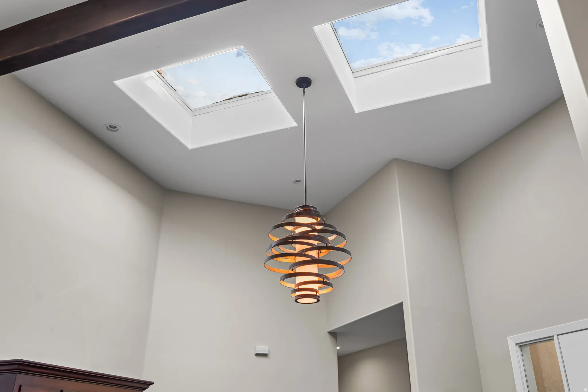 Vaulted ceiling featuring two skylights and a contemporary chandelier