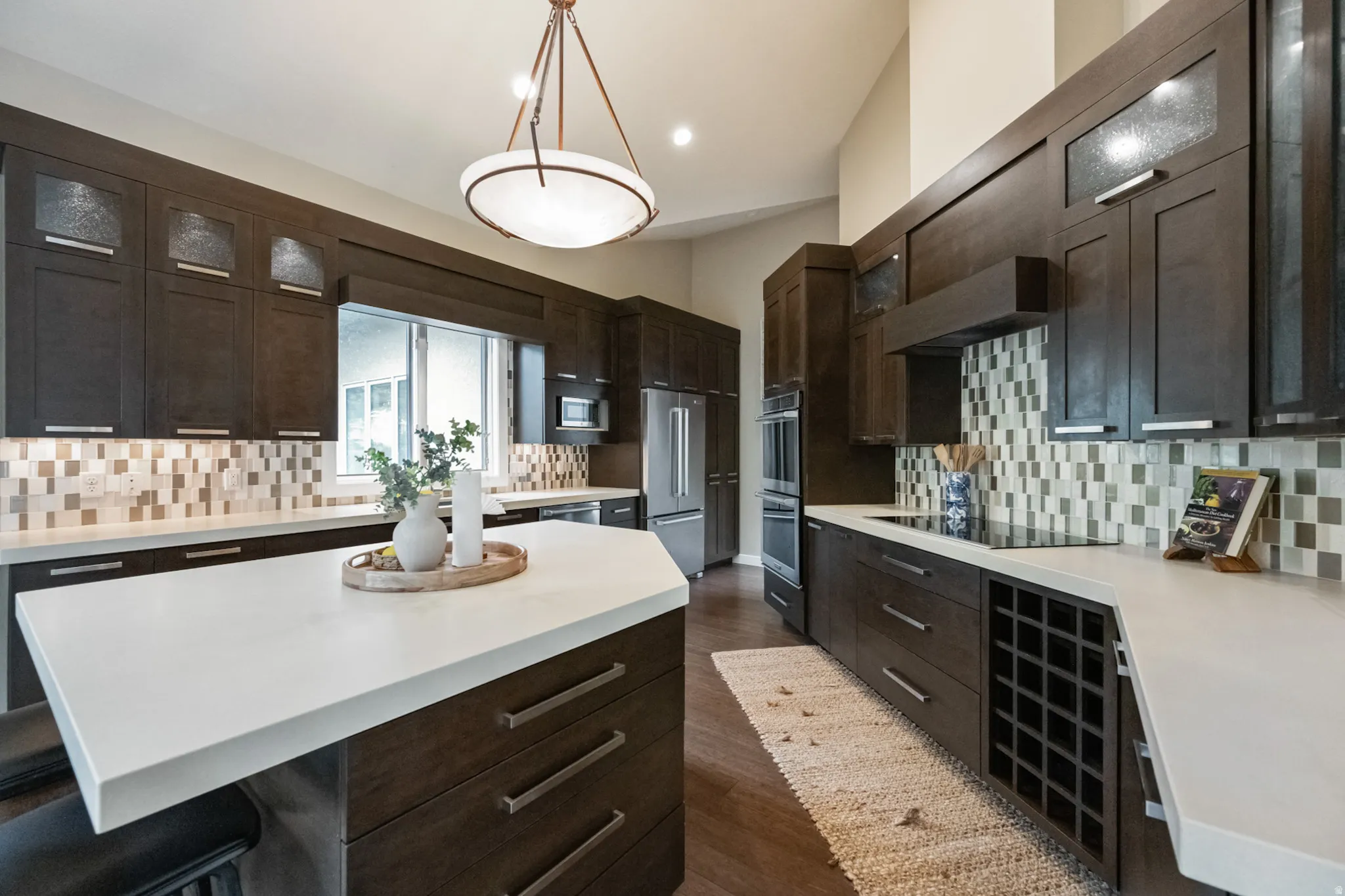 Modern kitchen featuring dark wood cabinetry, light countertops, and a mosaic tile backsplash