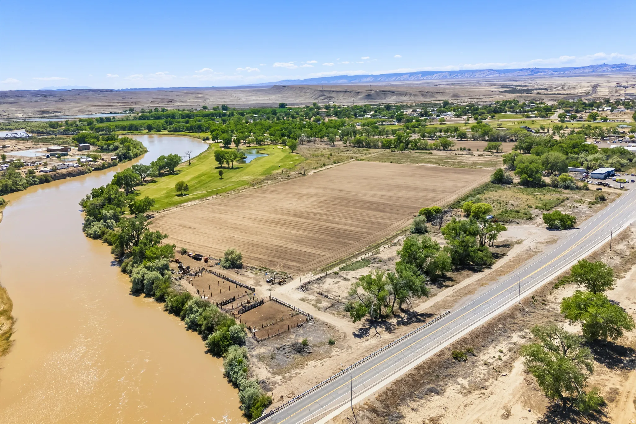 Expansive land parcel featuring river frontage, a cultivated field, and direct road access