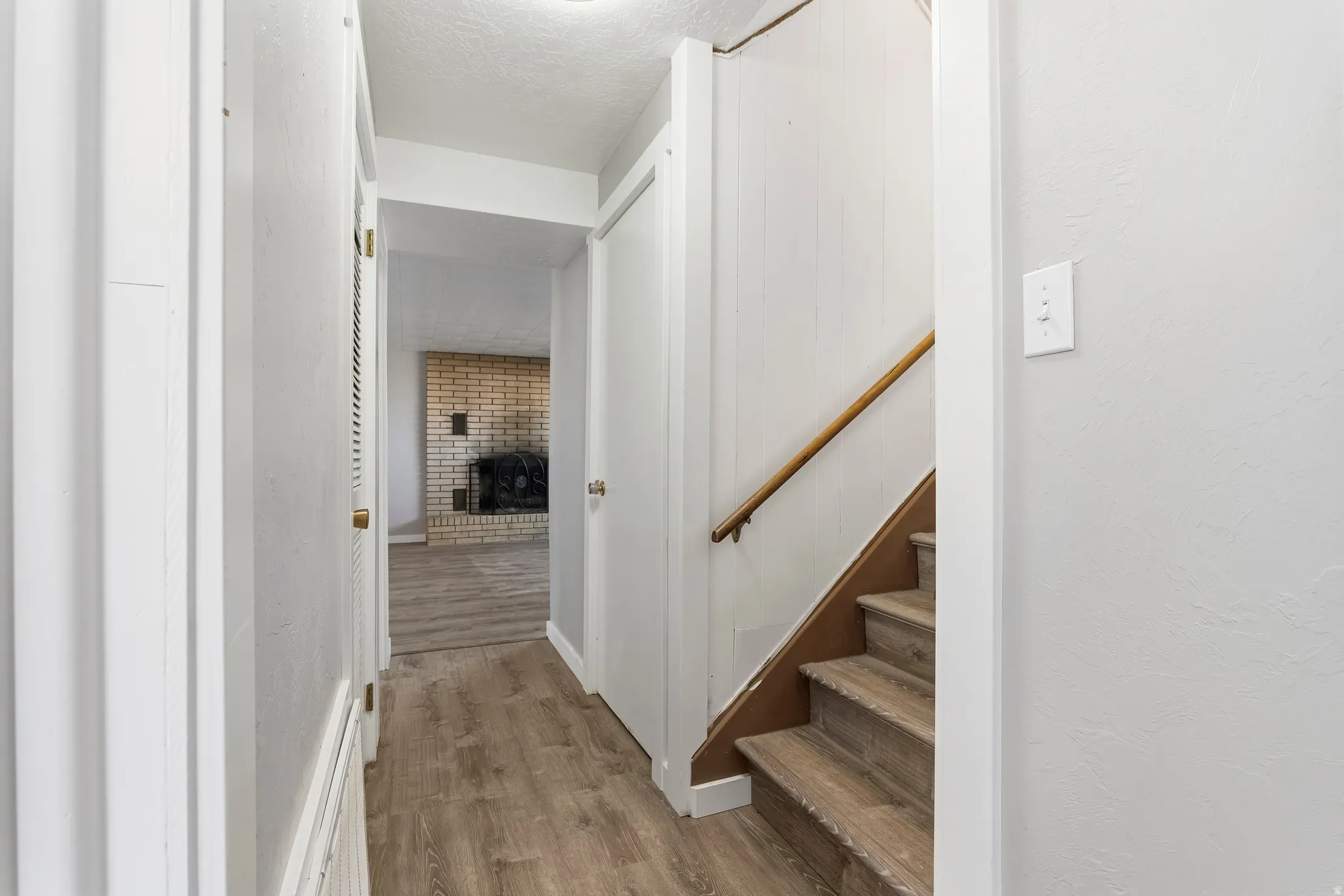 Hallway with light-toned wood-finish flooring, white painted walls, and white trim