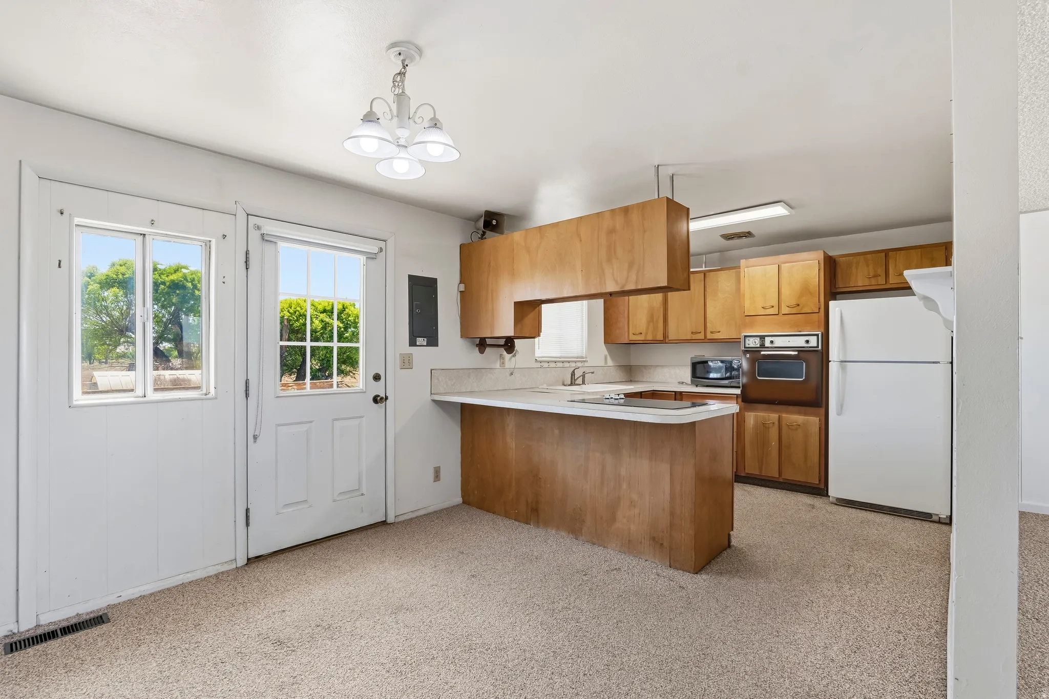 Kitchen featuring wood cabinetry, built-in oven, refrigerator, and an integrated cooktop on the peninsula