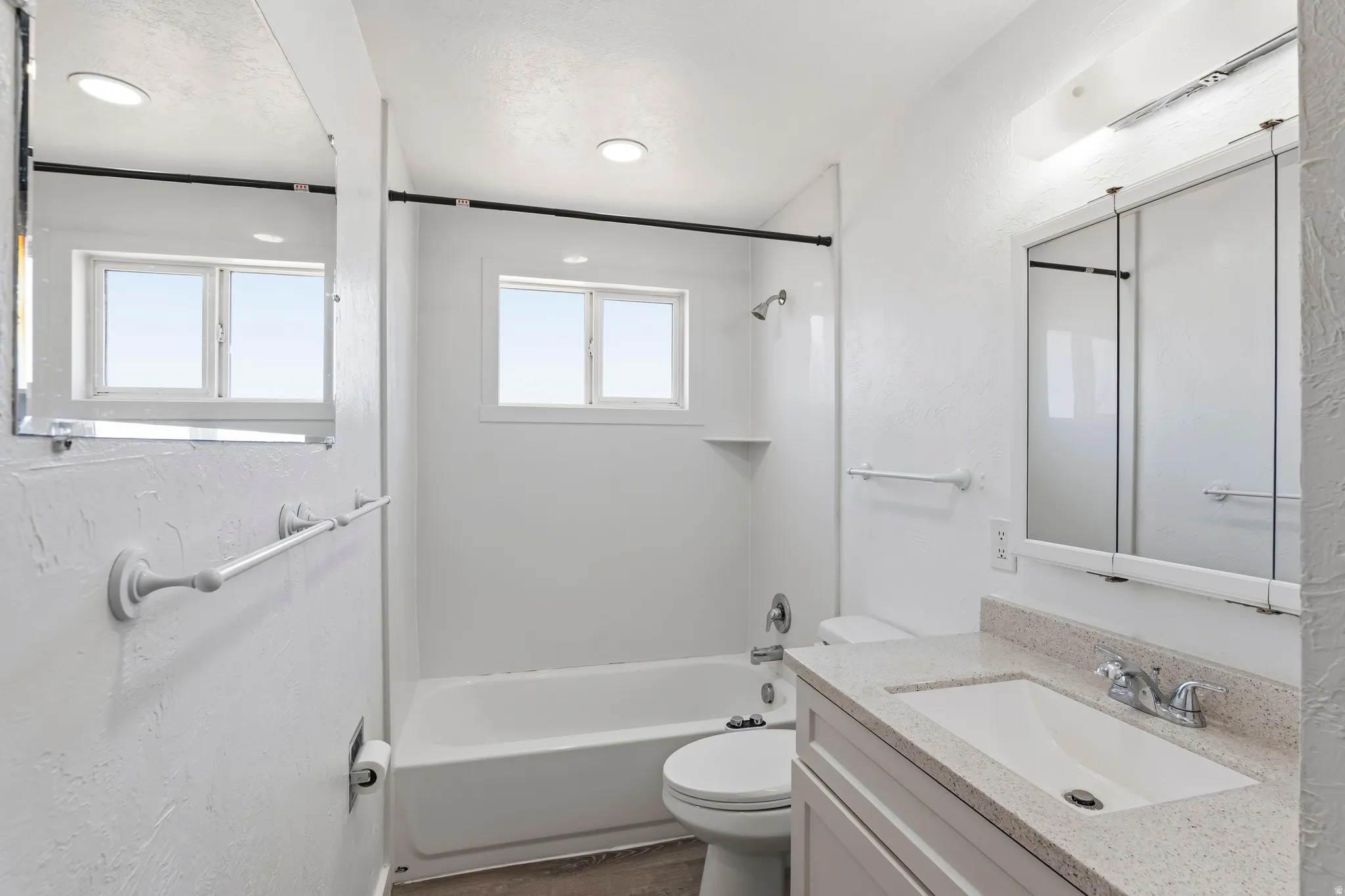 Bathroom featuring a single vanity with a white basin sink, light-toned countertop, and chrome faucet
