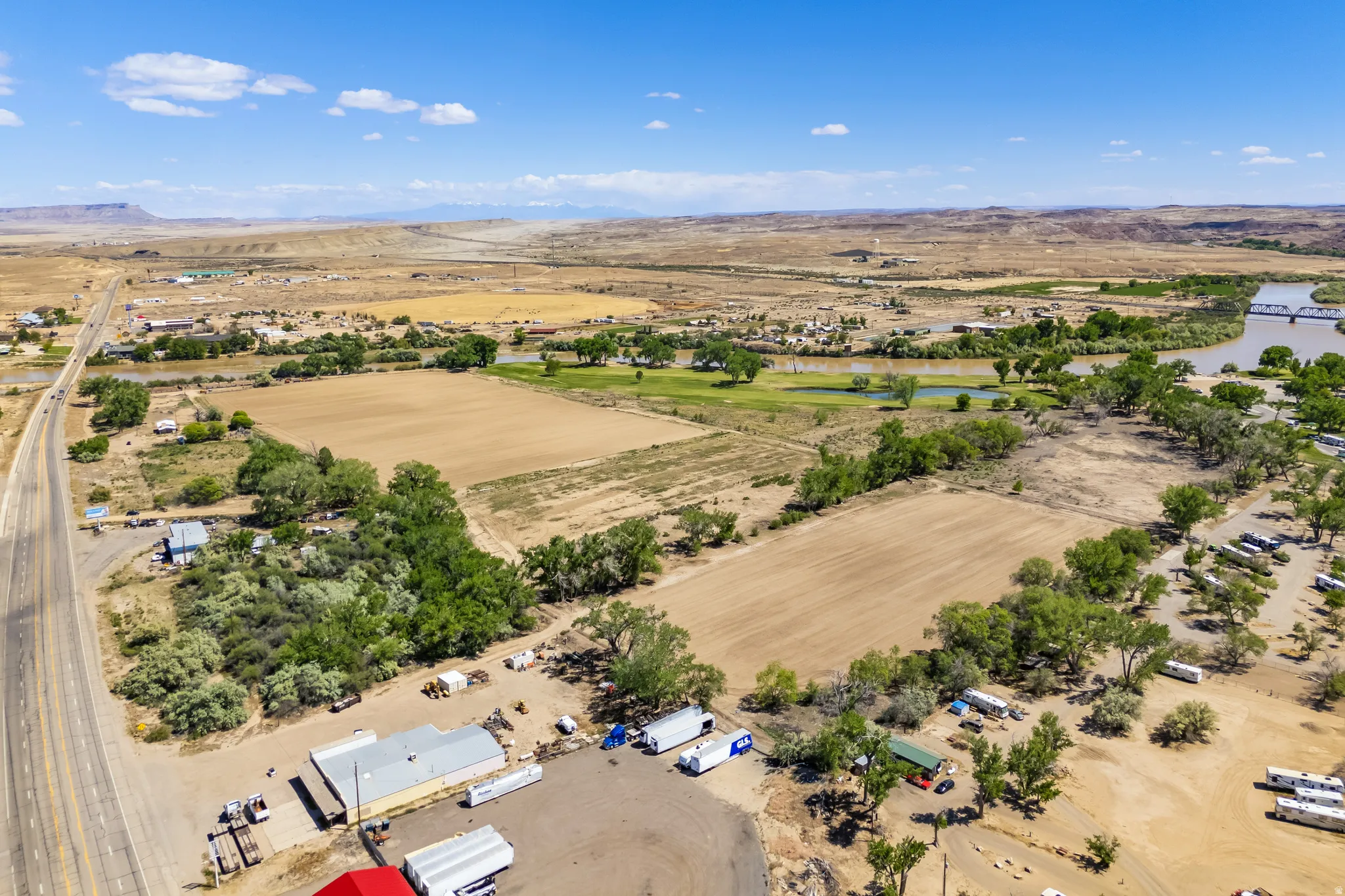 Expansive aerial landscape featuring multiple fields, a river, and distant arid terrain